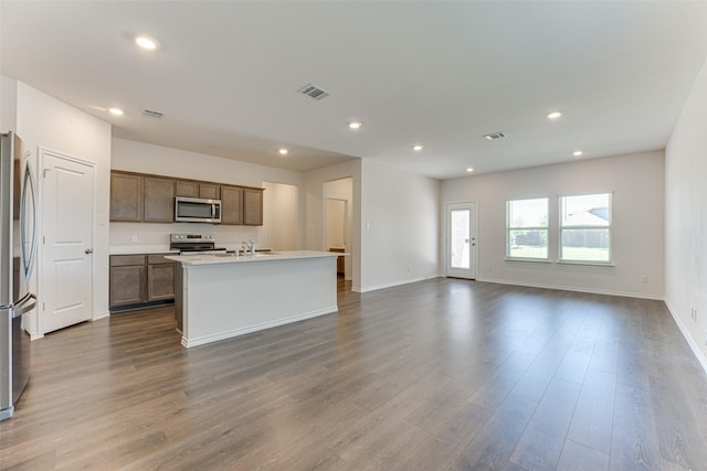 kitchen with an island with sink, visible vents, dark wood-type flooring, appliances with stainless steel finishes, and open floor plan