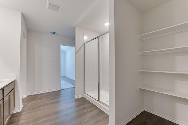 bathroom featuring vanity, wood finished floors, visible vents, and a shower stall