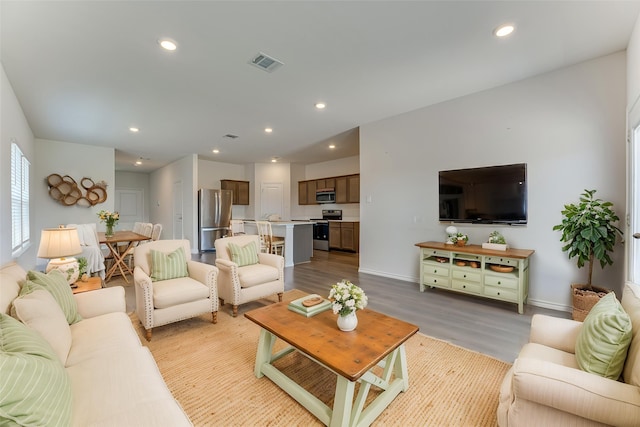 living room featuring baseboards, wood finished floors, visible vents, and recessed lighting
