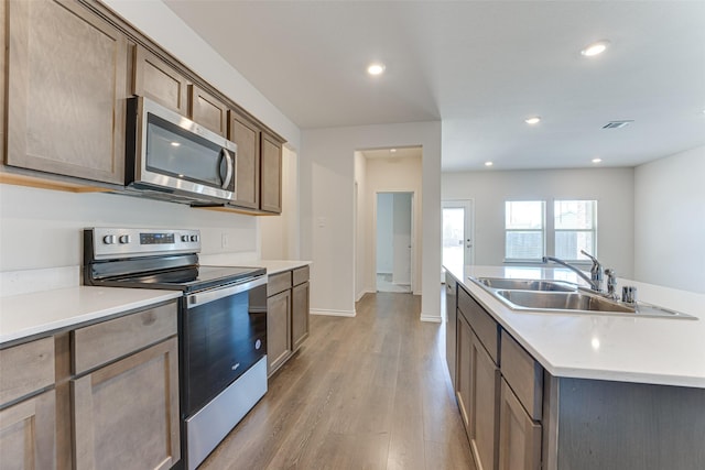 kitchen with light countertops, light wood-style floors, appliances with stainless steel finishes, and a sink