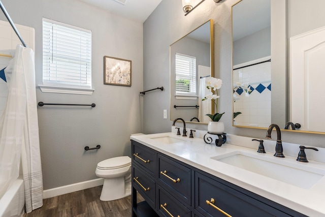 bathroom with wood finished floors, toilet, baseboards, and a sink