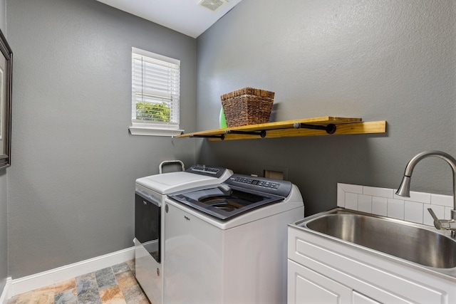 washroom featuring a sink, baseboards, stone finish floor, independent washer and dryer, and cabinet space