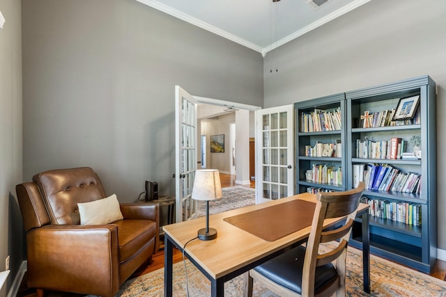 living area featuring a high ceiling, wood finished floors, french doors, crown molding, and baseboards