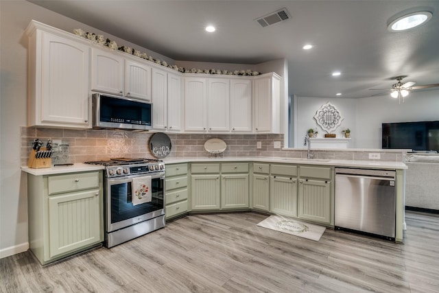 kitchen with a sink, open floor plan, appliances with stainless steel finishes, green cabinetry, and visible vents