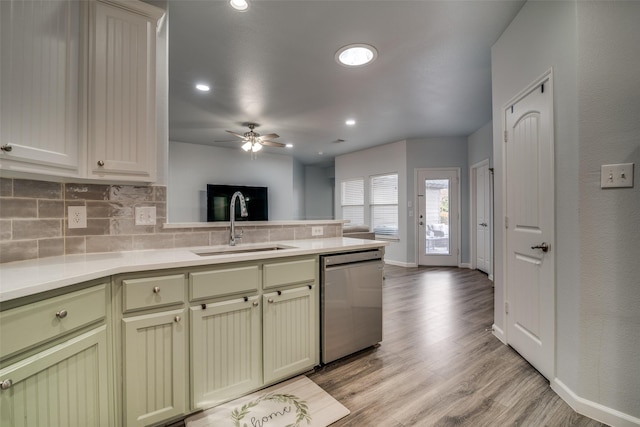 kitchen featuring a ceiling fan, stainless steel dishwasher, a sink, a peninsula, and tasteful backsplash