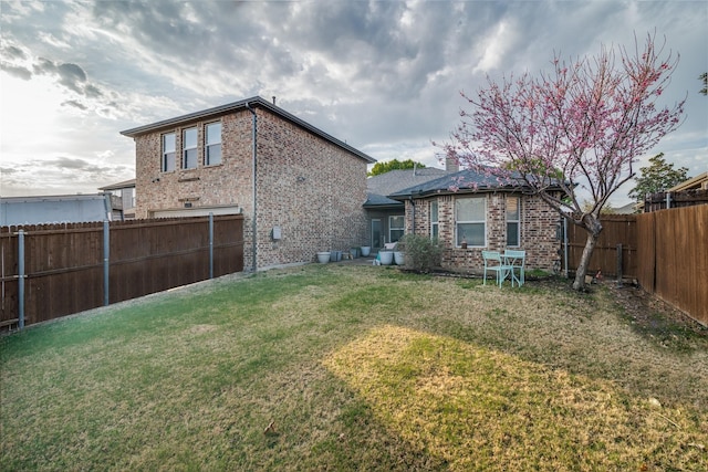 back of house with a lawn, a fenced backyard, and brick siding