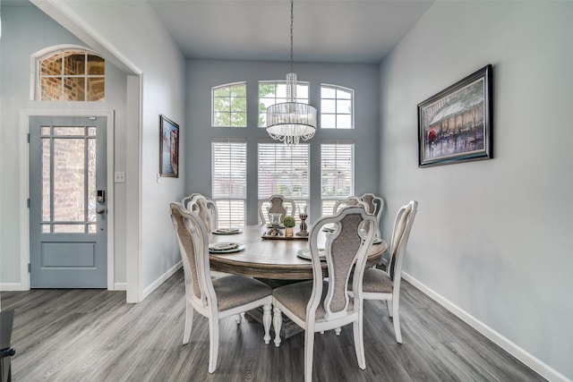 dining space with baseboards, wood finished floors, and a chandelier