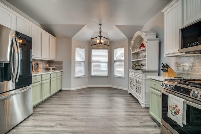 kitchen featuring light countertops, green cabinets, a chandelier, light wood-style flooring, and appliances with stainless steel finishes