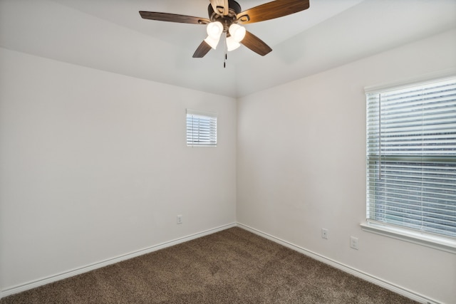 empty room featuring dark carpet, baseboards, and ceiling fan