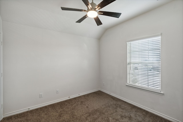 empty room featuring ceiling fan, plenty of natural light, dark carpet, and lofted ceiling