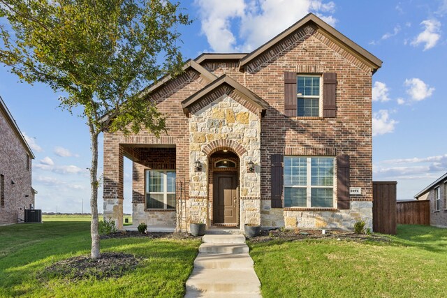 traditional-style home with a front yard, central AC, brick siding, and stone siding