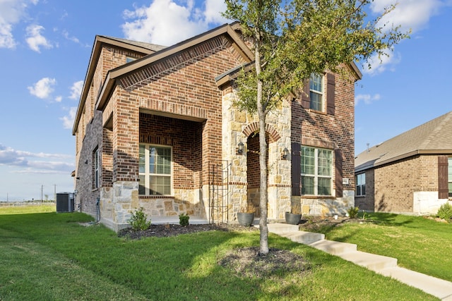 view of front of house featuring central AC unit, stone siding, a front lawn, and brick siding