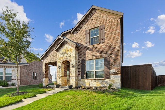 view of front of home with brick siding, a front yard, and stone siding