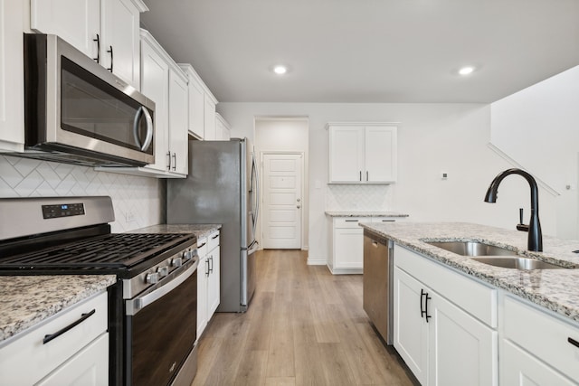 kitchen with light wood-type flooring, a sink, white cabinetry, and stainless steel appliances