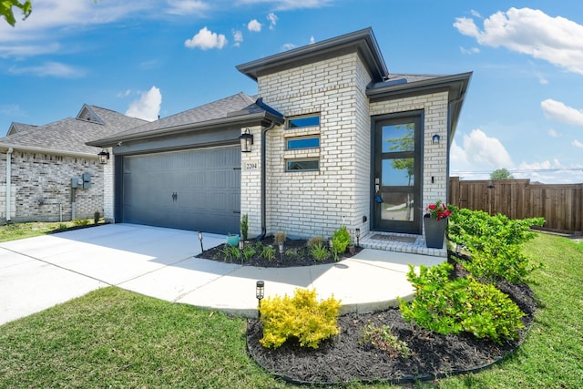 view of front facade featuring driveway, a front yard, brick siding, fence, and an attached garage
