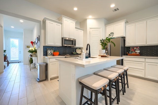 kitchen featuring a sink, appliances with stainless steel finishes, tasteful backsplash, and visible vents