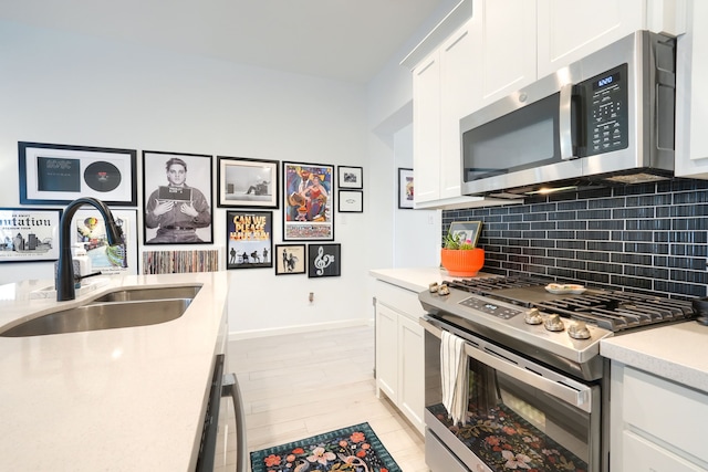 kitchen featuring backsplash, appliances with stainless steel finishes, a sink, light countertops, and white cabinetry