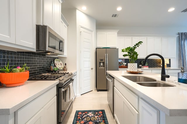 kitchen featuring backsplash, visible vents, a sink, white cabinets, and stainless steel appliances