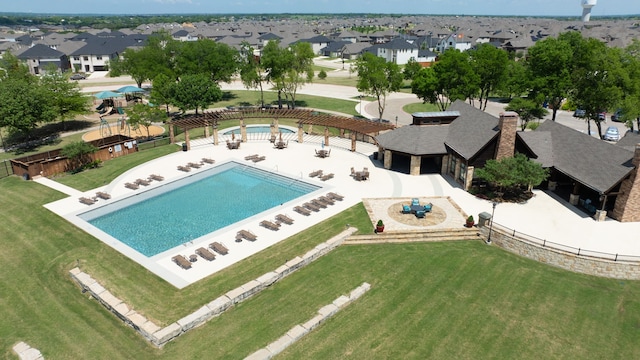 community pool with fence, a yard, and a residential view