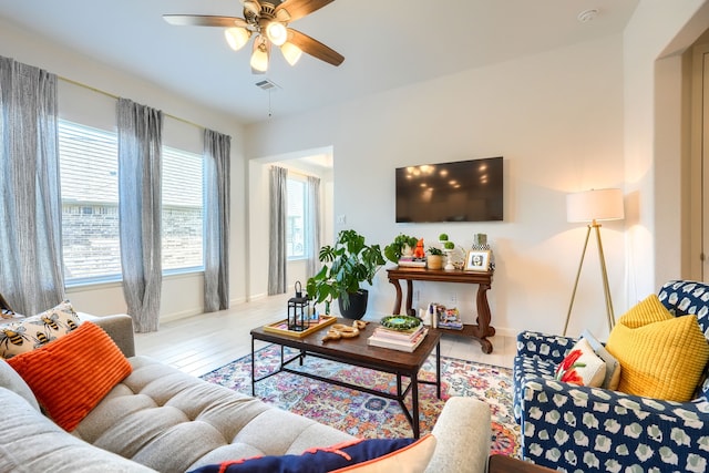 living area featuring visible vents, baseboards, ceiling fan, and wood finished floors
