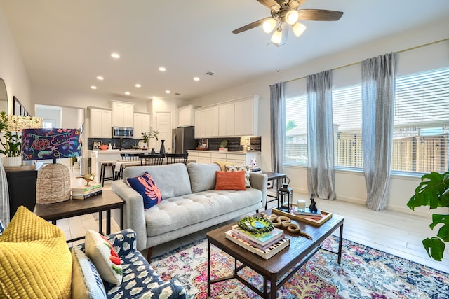 living area with recessed lighting, a ceiling fan, light wood finished floors, and baseboards