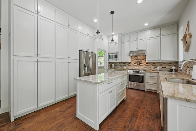 kitchen with recessed lighting, under cabinet range hood, a sink, decorative backsplash, and appliances with stainless steel finishes