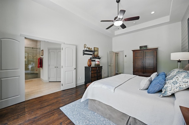 bedroom featuring recessed lighting, a high ceiling, a tray ceiling, wood finished floors, and ceiling fan