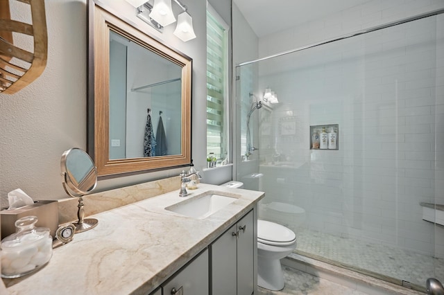 bathroom with a tile shower, toilet, and vanity