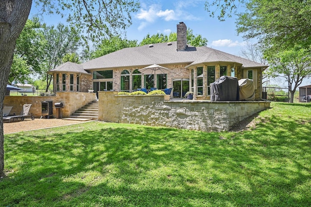 rear view of house featuring a chimney, fence, a yard, brick siding, and stairs