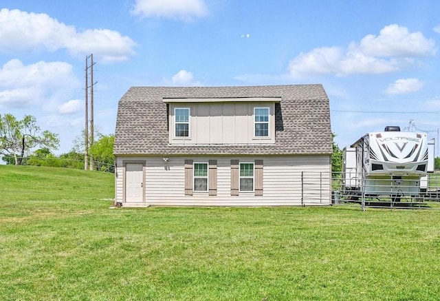 back of house featuring a gambrel roof, a yard, a shingled roof, and fence