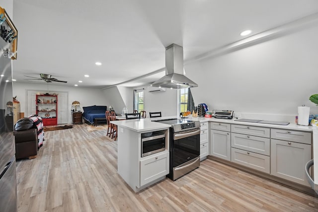 kitchen with island exhaust hood, light wood-style floors, a peninsula, appliances with stainless steel finishes, and open floor plan