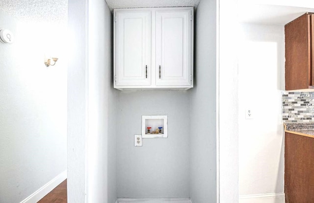 laundry area with baseboards, washer hookup, and cabinet space