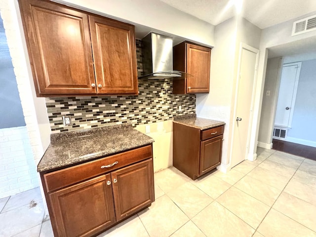 kitchen with visible vents, backsplash, dark stone counters, and wall chimney range hood