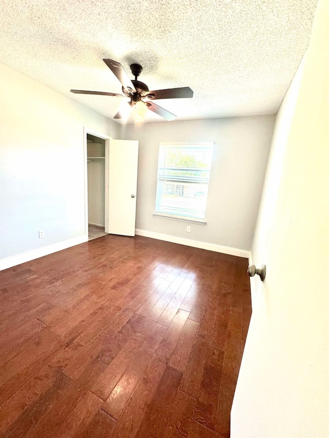 unfurnished bedroom featuring wood-type flooring, a closet, baseboards, a textured ceiling, and ceiling fan