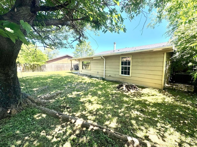 rear view of house featuring fence and a yard