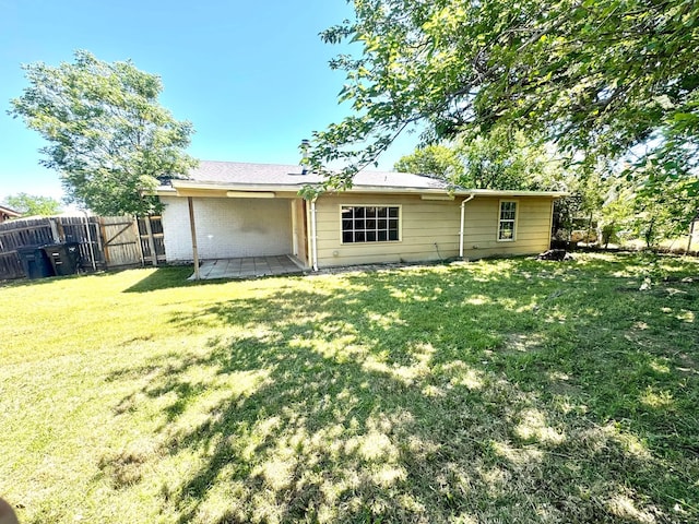 back of property with a patio area, a lawn, and fence
