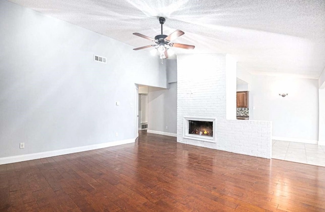 unfurnished living room featuring a brick fireplace, vaulted ceiling, visible vents, and ceiling fan