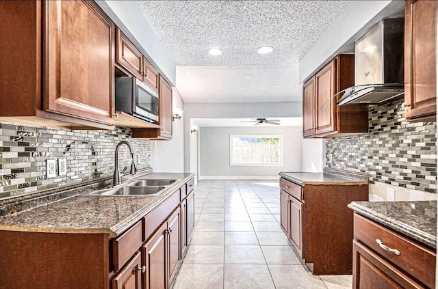 kitchen with a ceiling fan, a sink, a textured ceiling, decorative backsplash, and stainless steel microwave