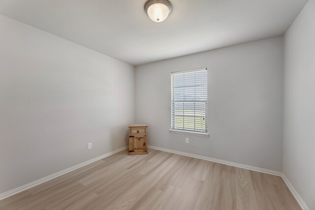 empty room with light wood finished floors and baseboards