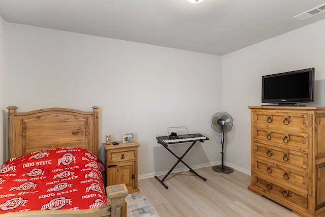 bedroom featuring light wood-style floors, visible vents, and baseboards