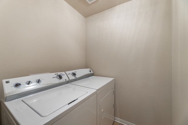 clothes washing area featuring washing machine and dryer, visible vents, and laundry area