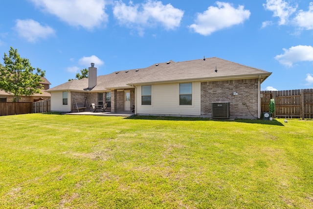 rear view of house with a lawn, a patio area, a fenced backyard, and brick siding