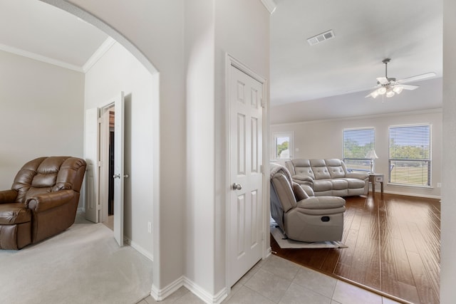 interior space featuring visible vents, a ceiling fan, arched walkways, crown molding, and baseboards