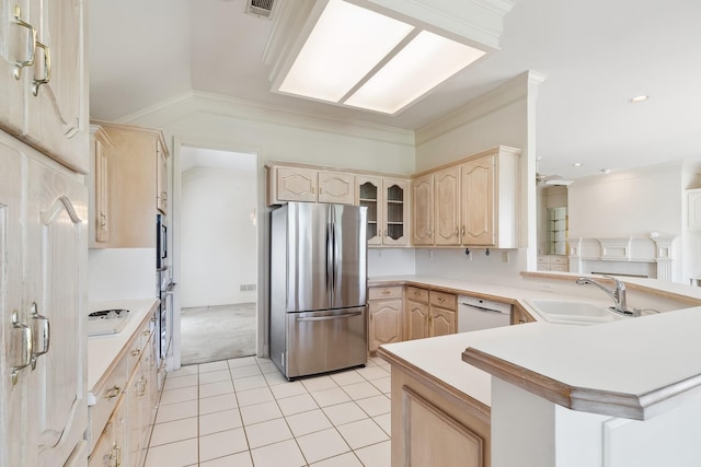 kitchen with a peninsula, appliances with stainless steel finishes, a sink, and light brown cabinetry