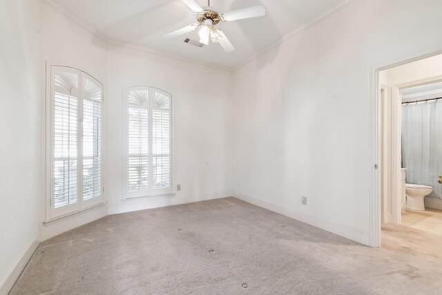 carpeted empty room with visible vents, a ceiling fan, baseboards, and ornamental molding