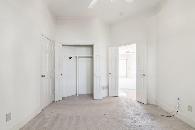 unfurnished bedroom with a ceiling fan, a closet, crown molding, baseboards, and light colored carpet