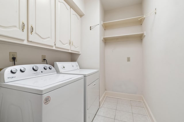 laundry area with washing machine and dryer, baseboards, cabinet space, and light tile patterned floors