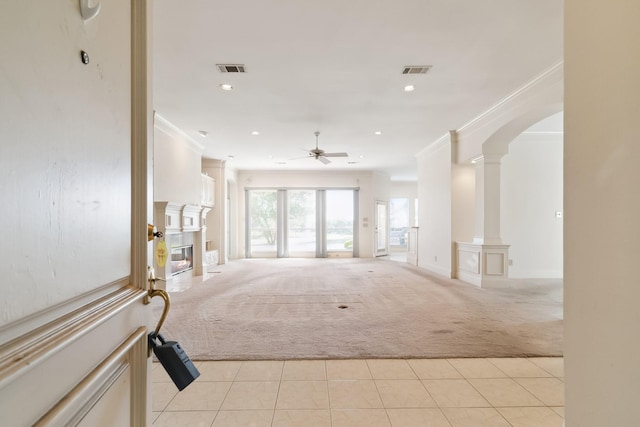 interior space with visible vents, a ceiling fan, ornamental molding, arched walkways, and light colored carpet