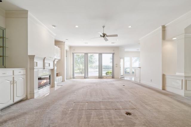 unfurnished living room with recessed lighting, a ceiling fan, crown molding, a fireplace, and light colored carpet