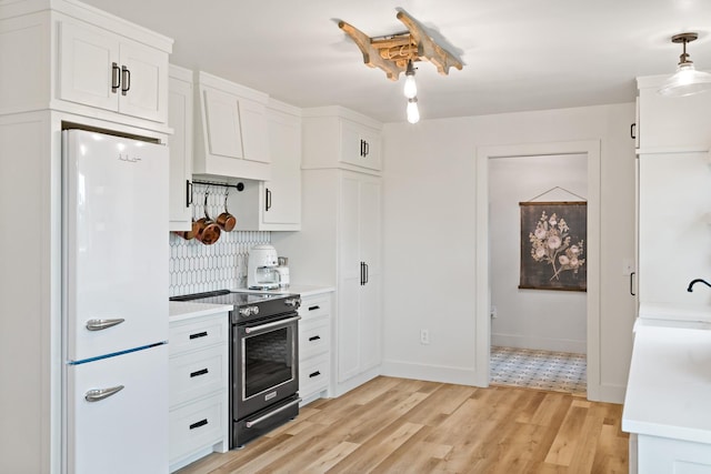 kitchen with light countertops, freestanding refrigerator, white cabinetry, and stainless steel range with electric stovetop